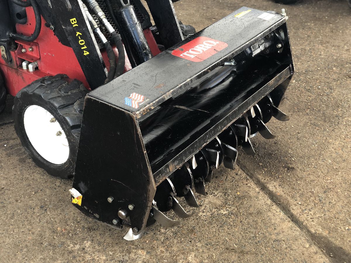 At Online Hire we hire mini skid steer loaders; this image shows a rotary hoe attachment from the left hand side